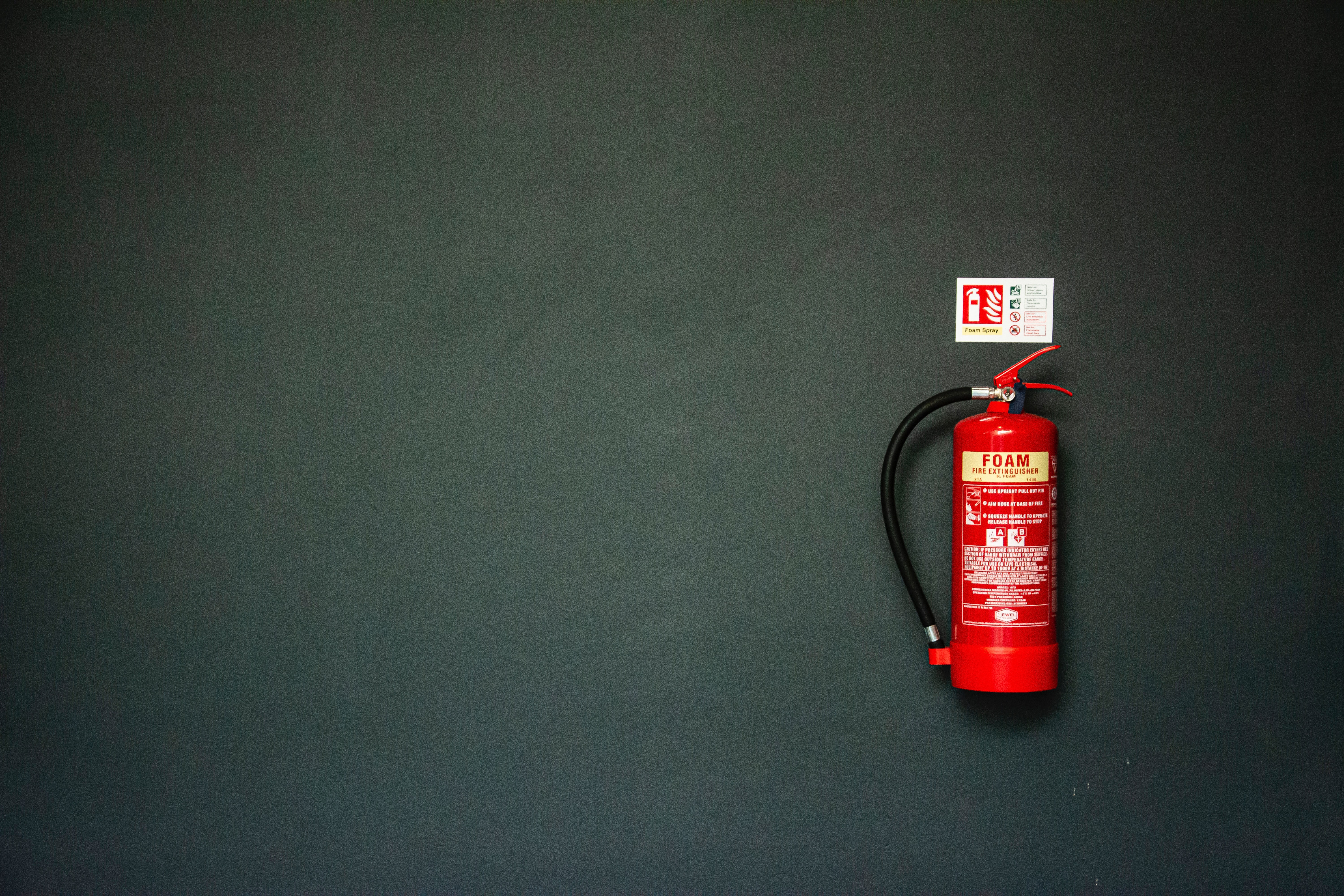 red foam fire extinguisher on a black wall