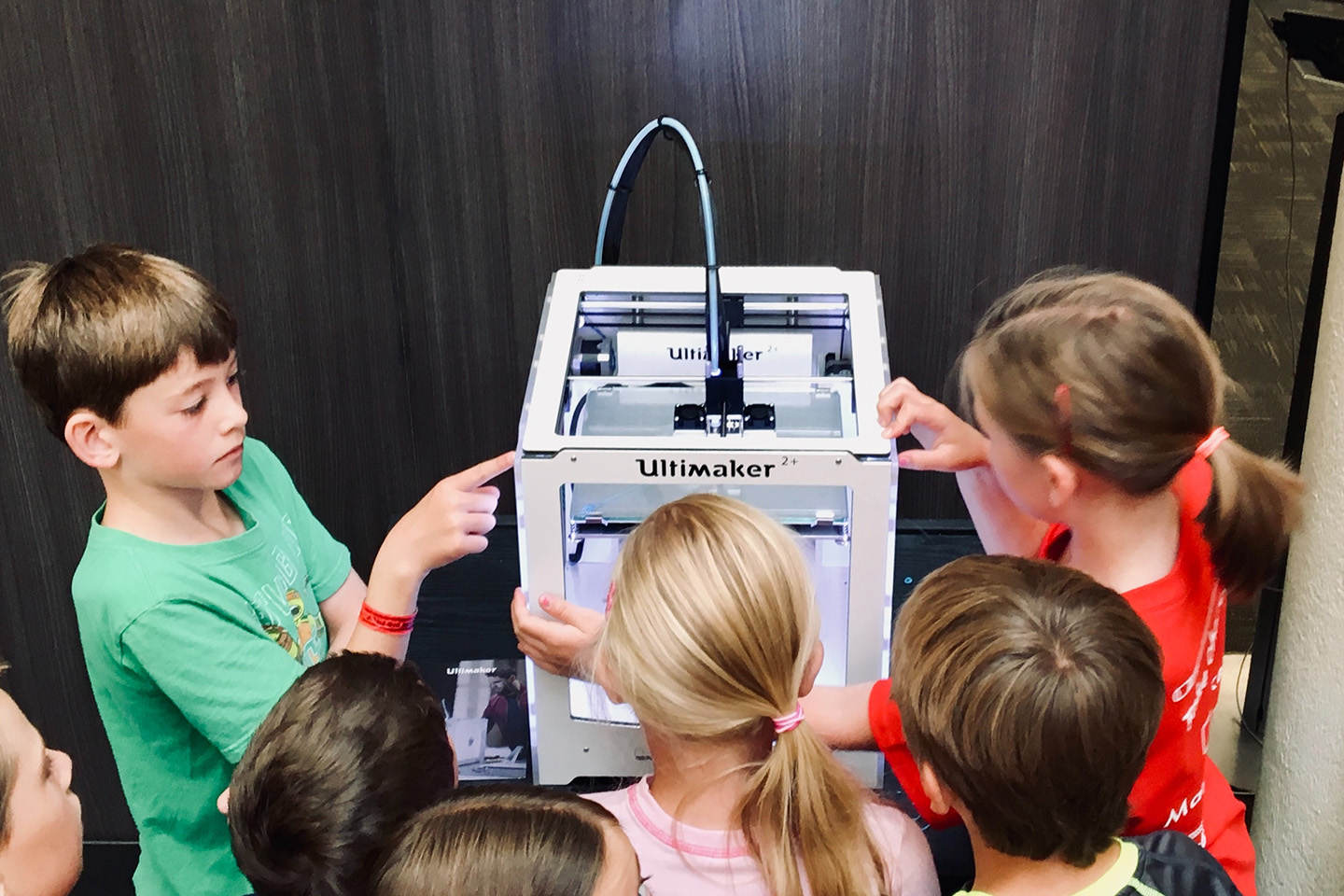 kids looking at a white 3d printer