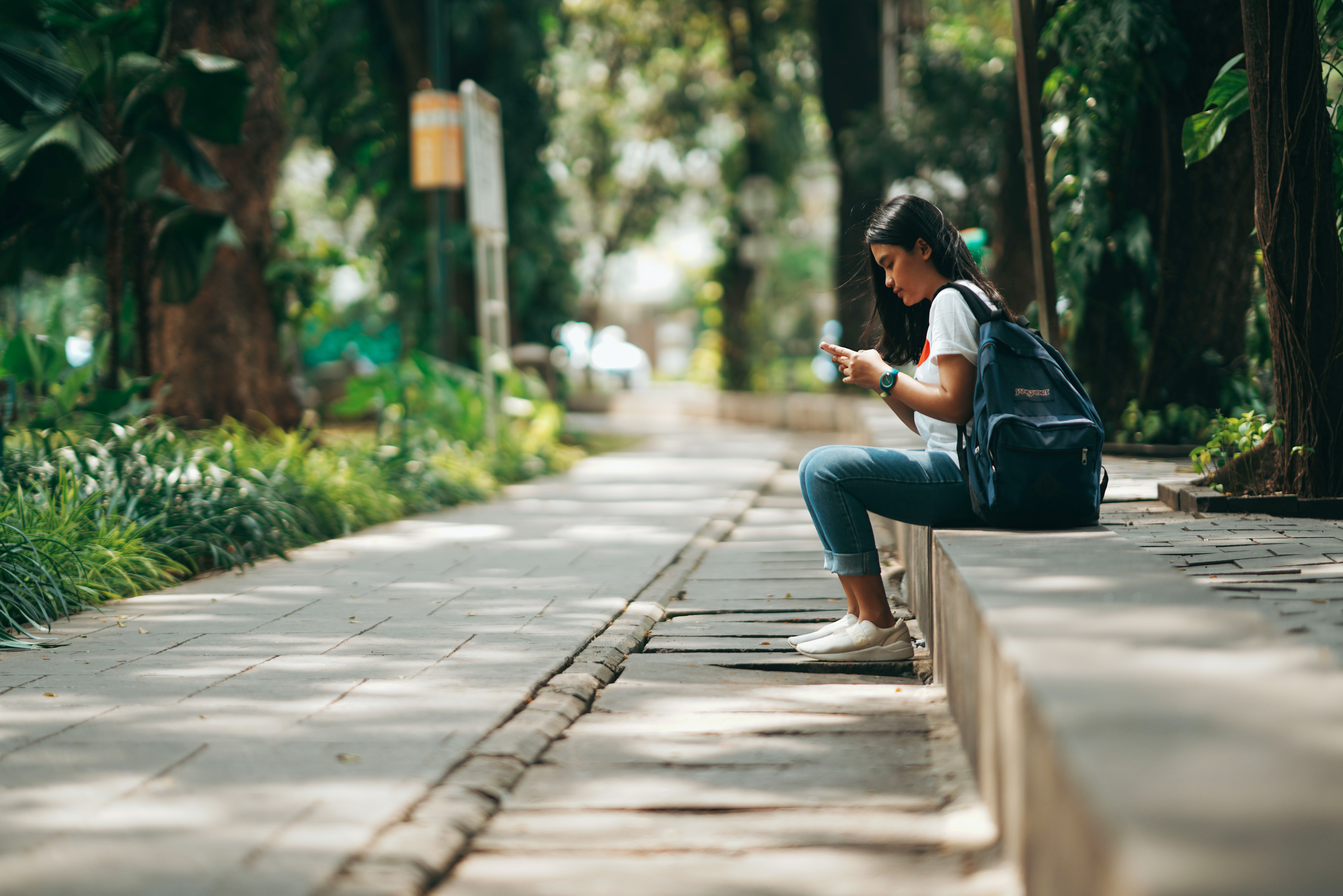 Young woman sitting in park looking on phone