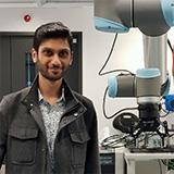 Anirban standing next to a robotic machine